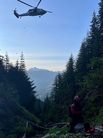 A Naval Air Station Search and Rescue helicopter is positioned to pick up an injured speed-flyer who crashed on Church Mountain, Wash. July 3, 2023.