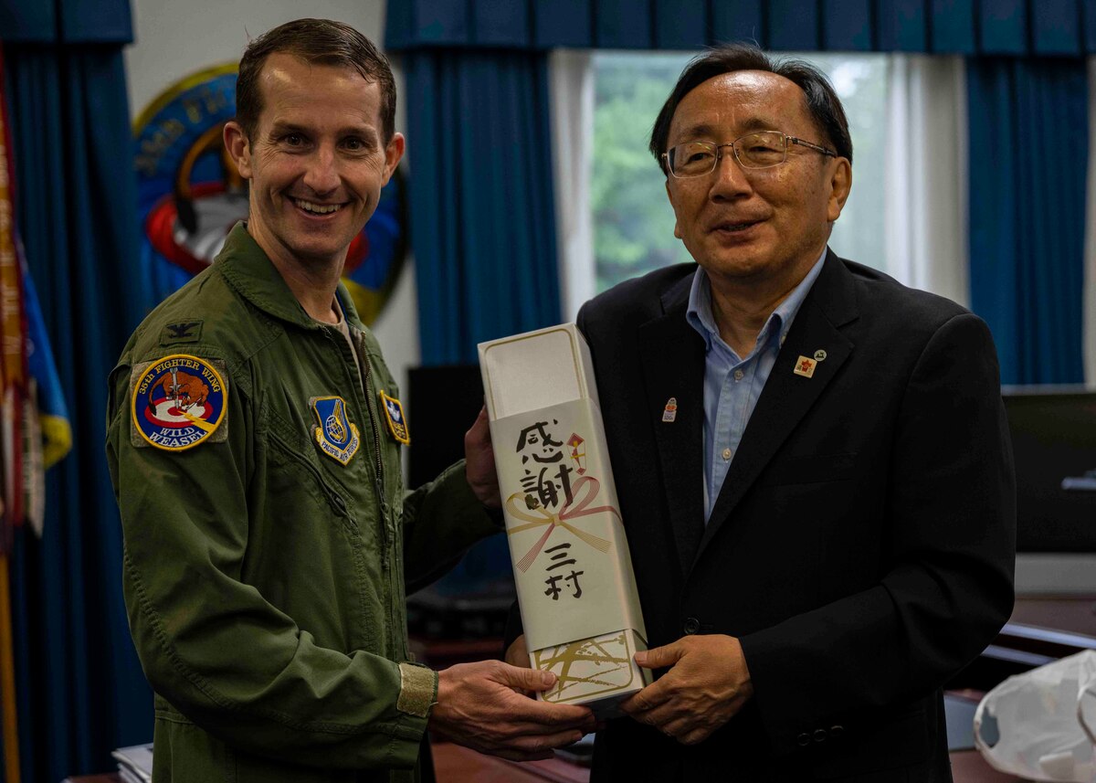 Two people pose with a group photo while holding a gift.