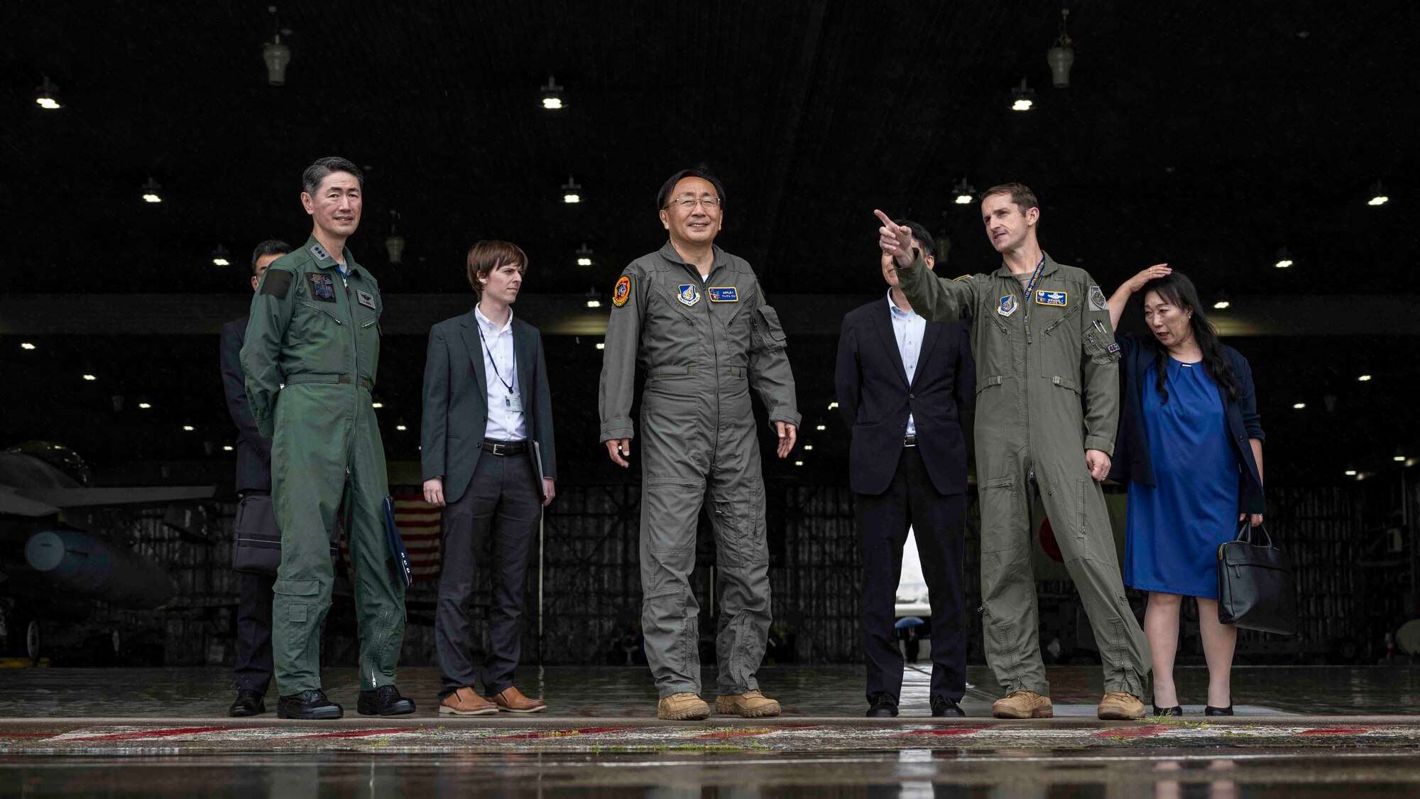 Group of people look out on the flightline at fighter jets.