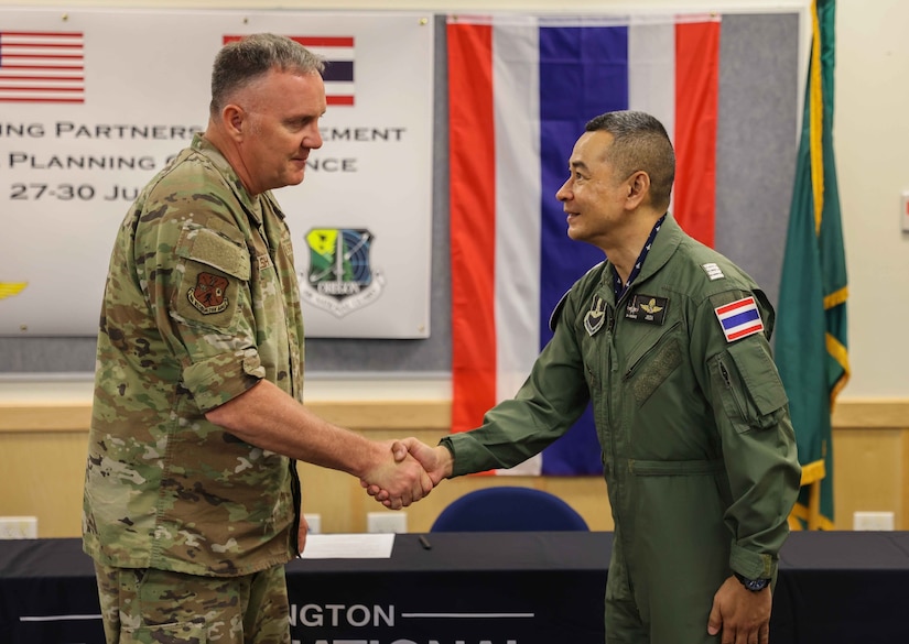 An airman shakes hands with a Thai service member.