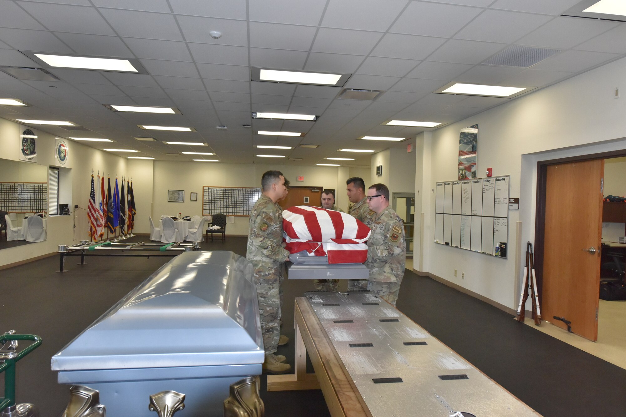 Honor Guard members lift a flag-draped practice casket.