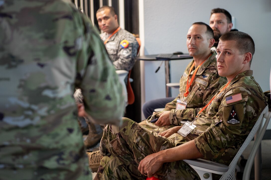Men in military uniforms listening to a briefing