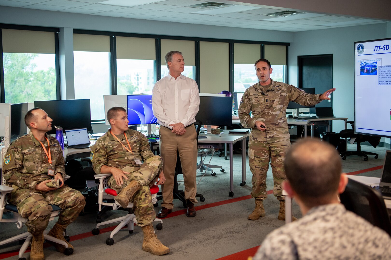 Man in military uniform briefing room full of people