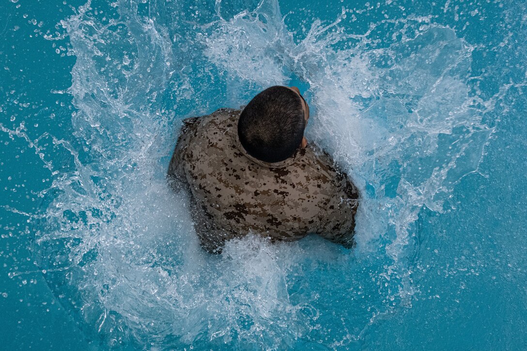 A Marine jumps into a pool as seen from above.