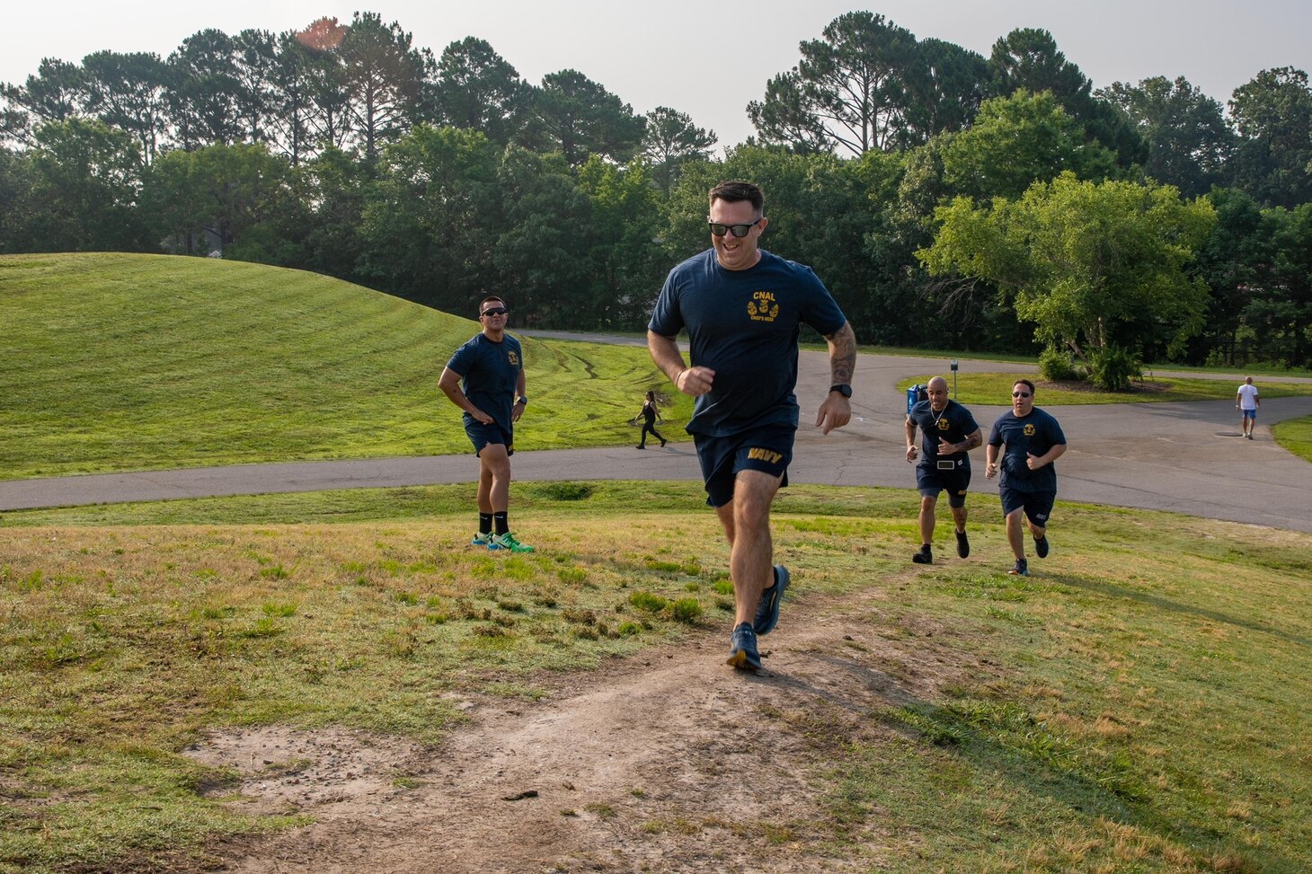 Sailors run up a grass hill