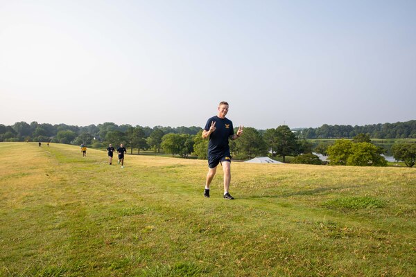 Sailor posing for a photo while running on a grass field