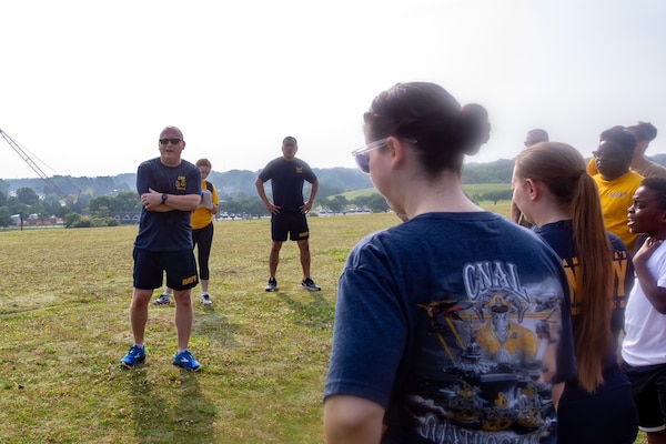 Sailors in physical training gear stand in a crowd