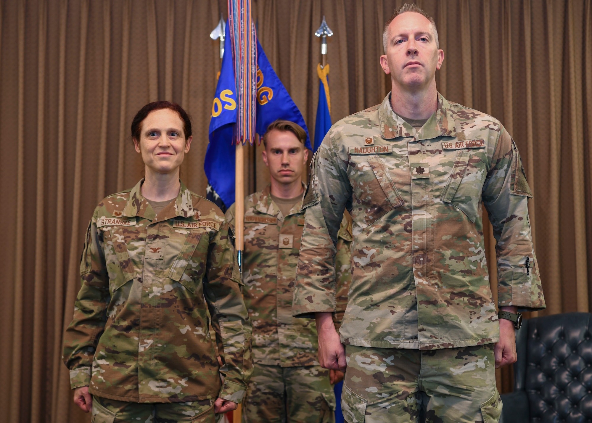 Three people in green uniforms stand for a photo.