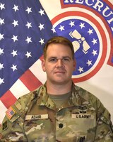 Male Army Solider poses in front of the United States and USAREC flags.