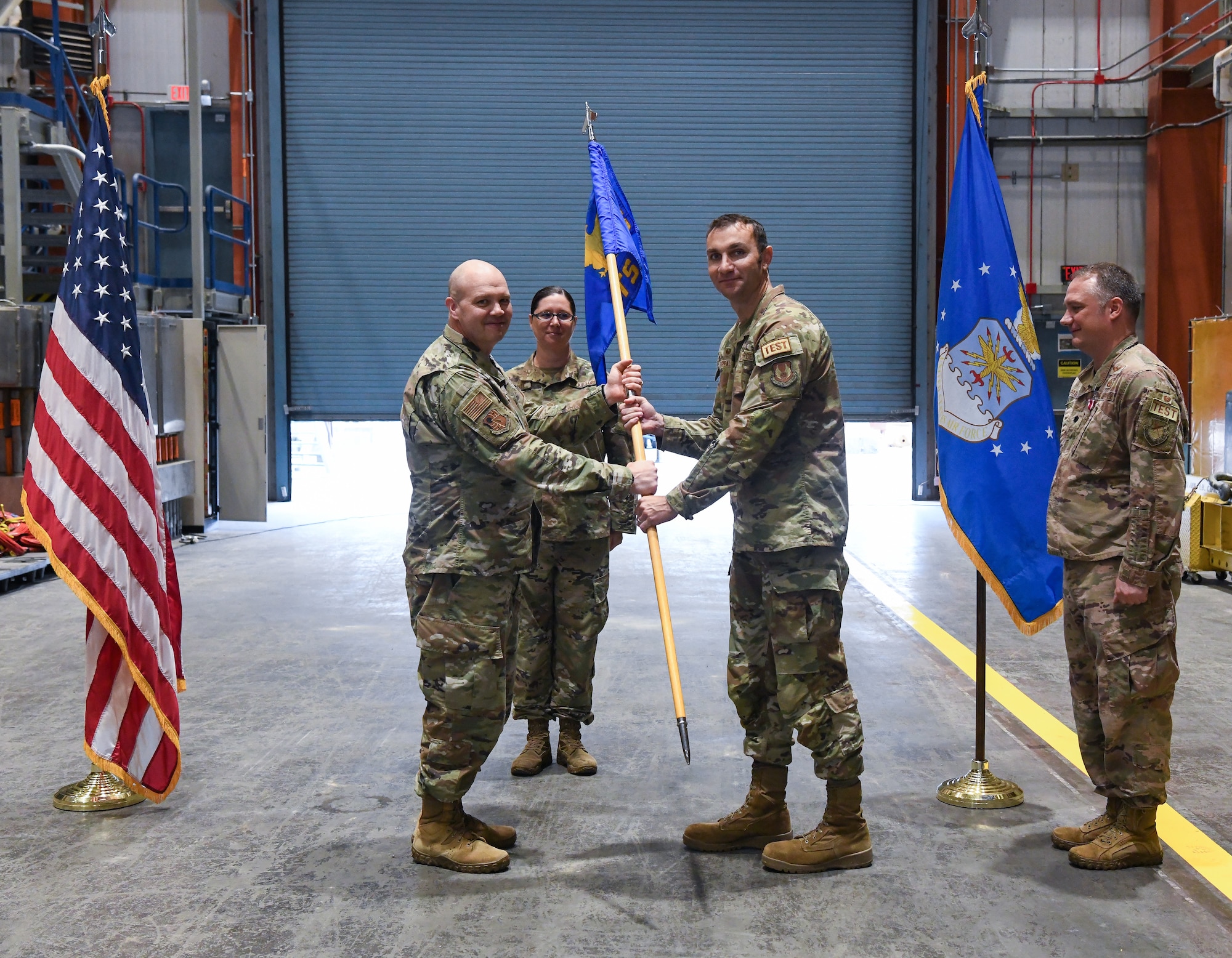 Col. Jason Vap, left, commander of the 804th Test Group, Arnold Engineering Development Complex, passes the 718th Test Squadron guidon to Lt. Col. Bradley Breaux charging him with leadership of the squadron during a change of leadership ceremony at Arnold Air Force Base, Tenn., June 15, 2023. Also pictured at right is Lt. Col. Dayvid Prahl, who relinquished leadership of the squadron during the ceremony. (U.S. Air Force photo by Jill Pickett)