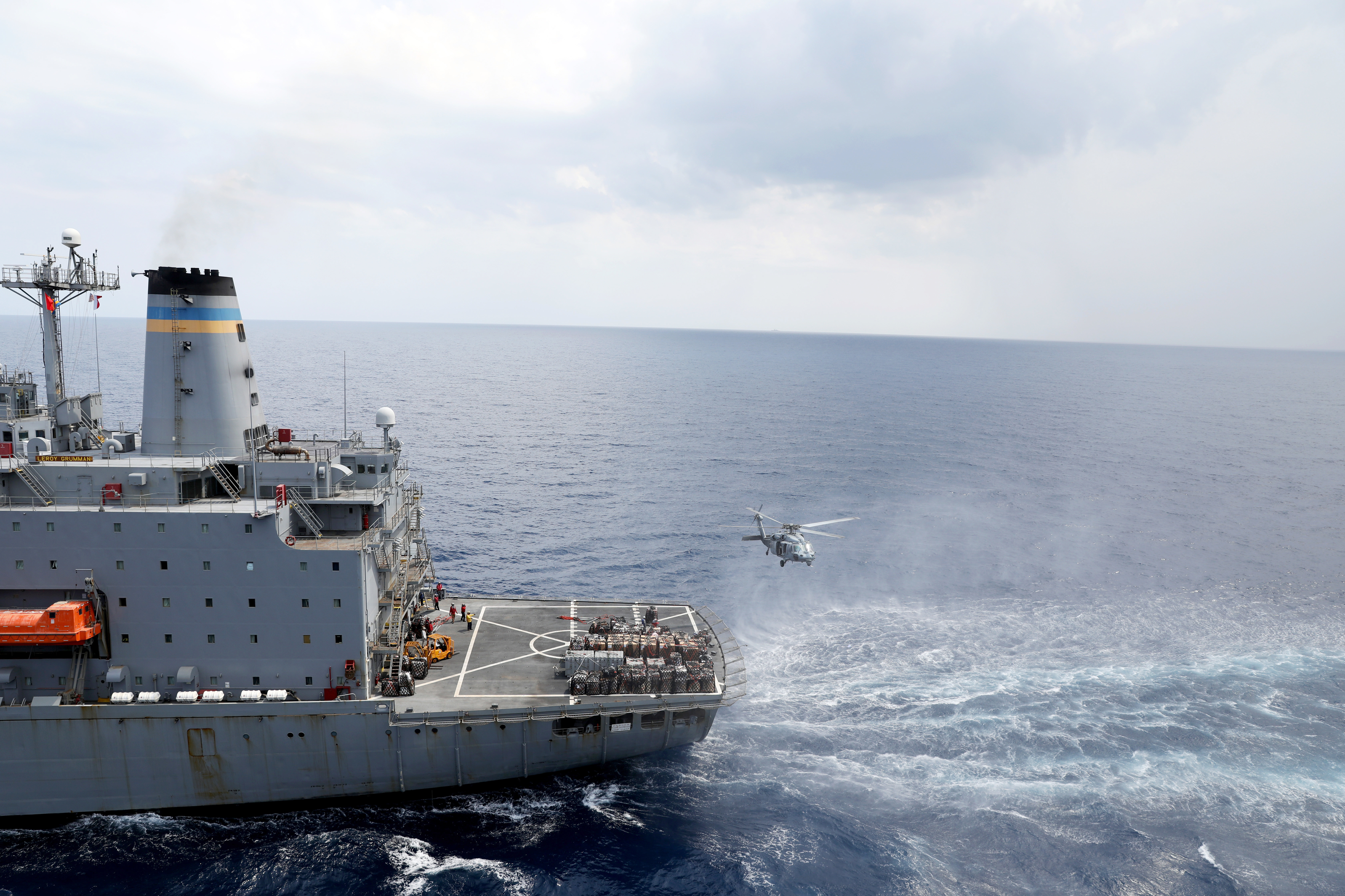 An MH-60R helicopter approaches USNS Leroy Grumman (T-A0 195) during a replenishment-at-sea.