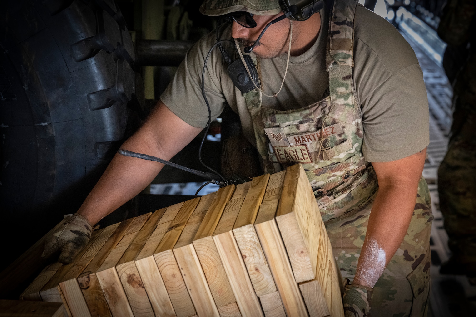 U.S. Air Force Staff Sgt. Andres Martinez, right, a 621st Mobility Support Operations Squadron enlisted air/ground liason element (EAGLE) team member, carries some wood blocks during Exercise SWAMP AVENGER at North Field, South Carolina, May 25, 2023.