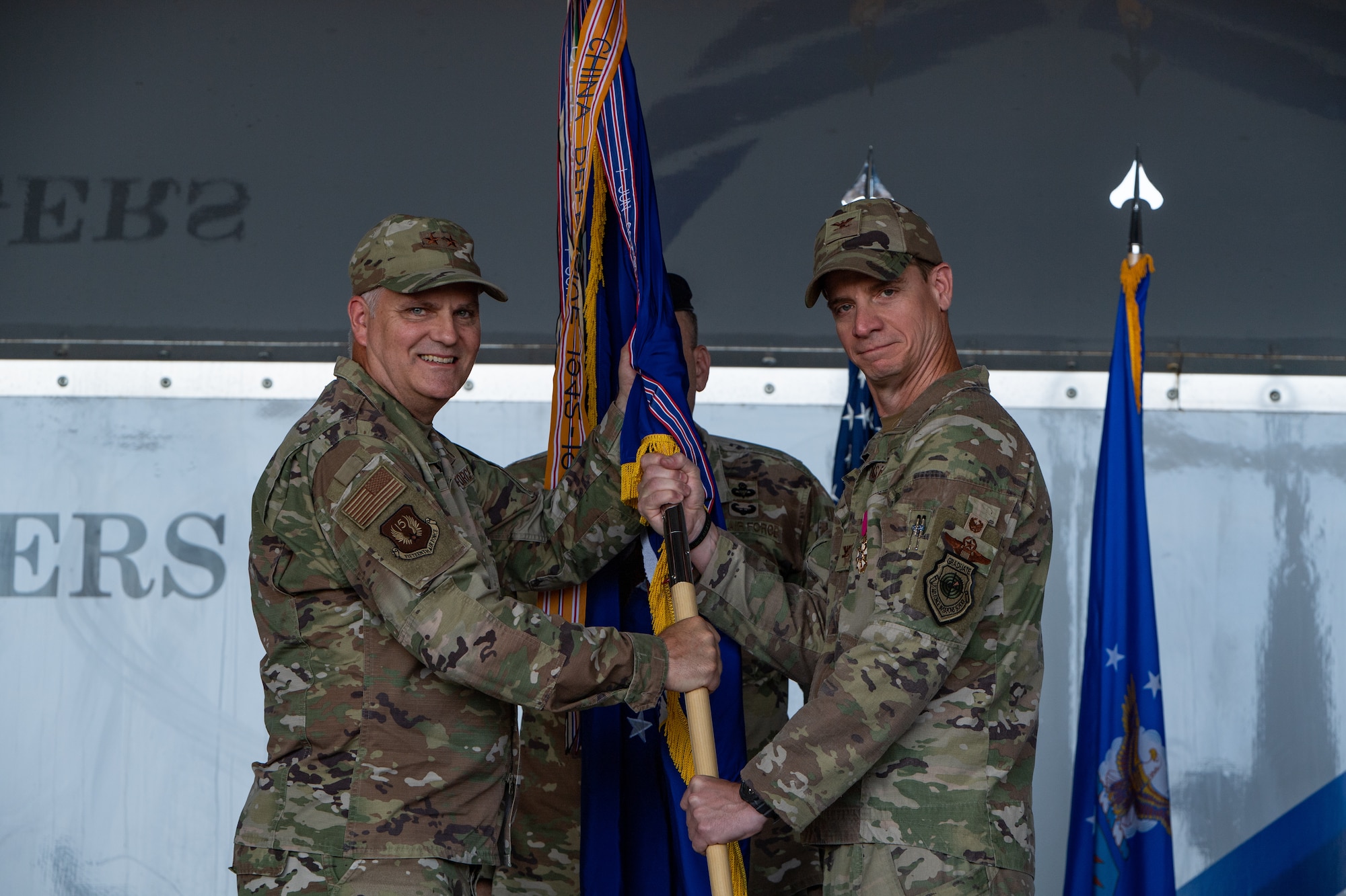 U.S. Air Force Col. Russ Cook, outgoing 23rd Wing commander, right, passes a guidon to Maj. Gen. Mike Koscheski, 15th Air Force commander and presiding officer, left, during a change of command ceremony at Moody Air Force Base, Georgia, June 6, 2023. The 23rd Wing provides Combat Search and Rescue and personnel recovery capabilities by employing HC-10J Combat King IIs, HH-60W Jolly Green IIs, and A-10C Thunderbolt II aircraft. The passing of the guidon symbolizes the hand-off of authority to the incoming commander. (U.S. Air Force photo by Andrea Jenkins)