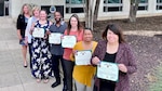 a group of people hold certificates and medals