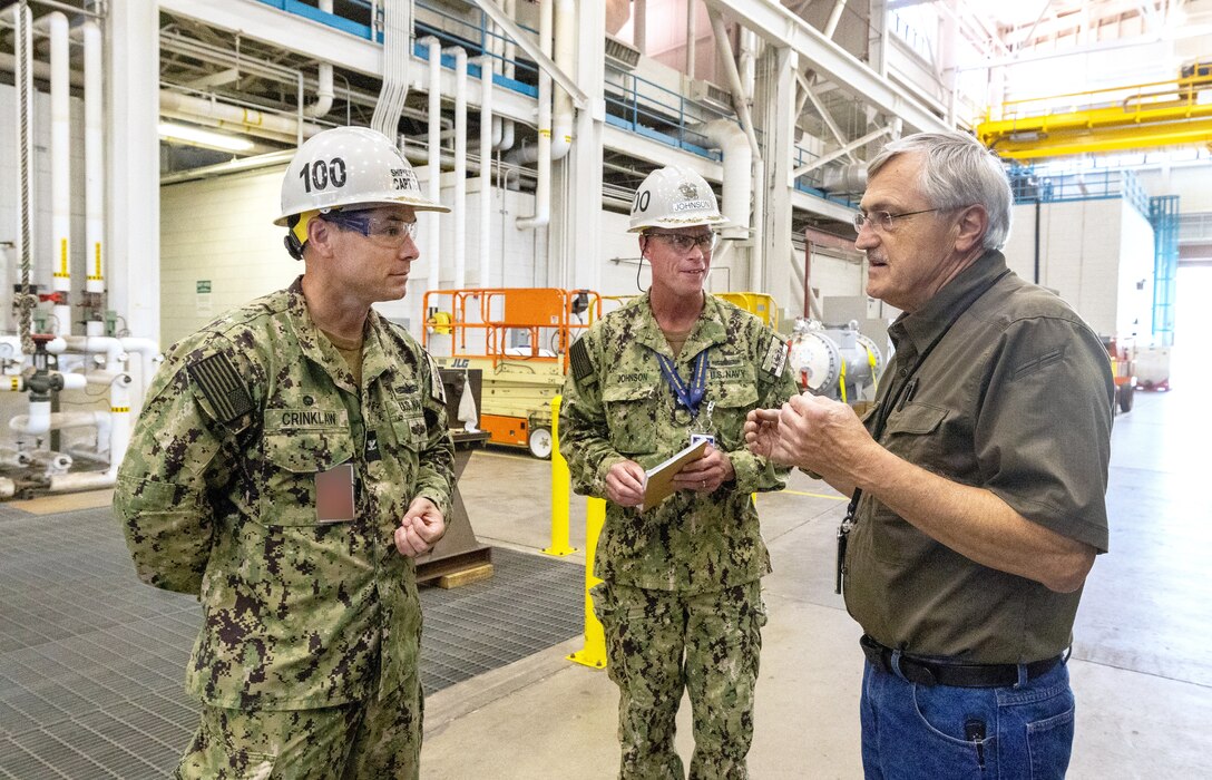 Capt. JD Crinklaw, left, commander, Puget Sound Naval Shipyard & Intermediate Maintenance Facility, and Cmdr. Brandon Johnson, PSNS & IMF executive officer, visit with Bill Schoonmaker, supervisor, Shop 31, Inside Machinist, June 27, 2023, during their tour of the San Diego Detachment. (U.S Navy Photo by Wendy Hallmark)