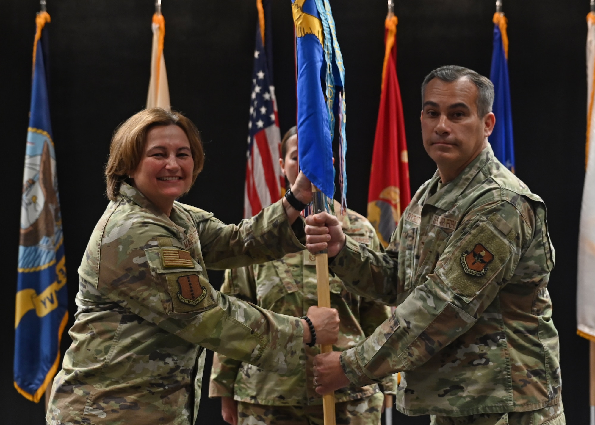 U.S. Air Force Col. Angelina Maguinness, 17th Training Wing commander, passes the guidon to Col. Ian Rybczynski, incoming 17th Medical Group commander, during the change of command ceremony at the Powell Event Center, Goodfellow Air Force Base, Texas, July 6, 2023. Rybczynski was previously the 59th Medical Wing Biomedical Science Executive at Joint Base San Antonio-Lackland, Texas. (U.S. Air Force photo by Airman 1st Class Zach Heimbuch)