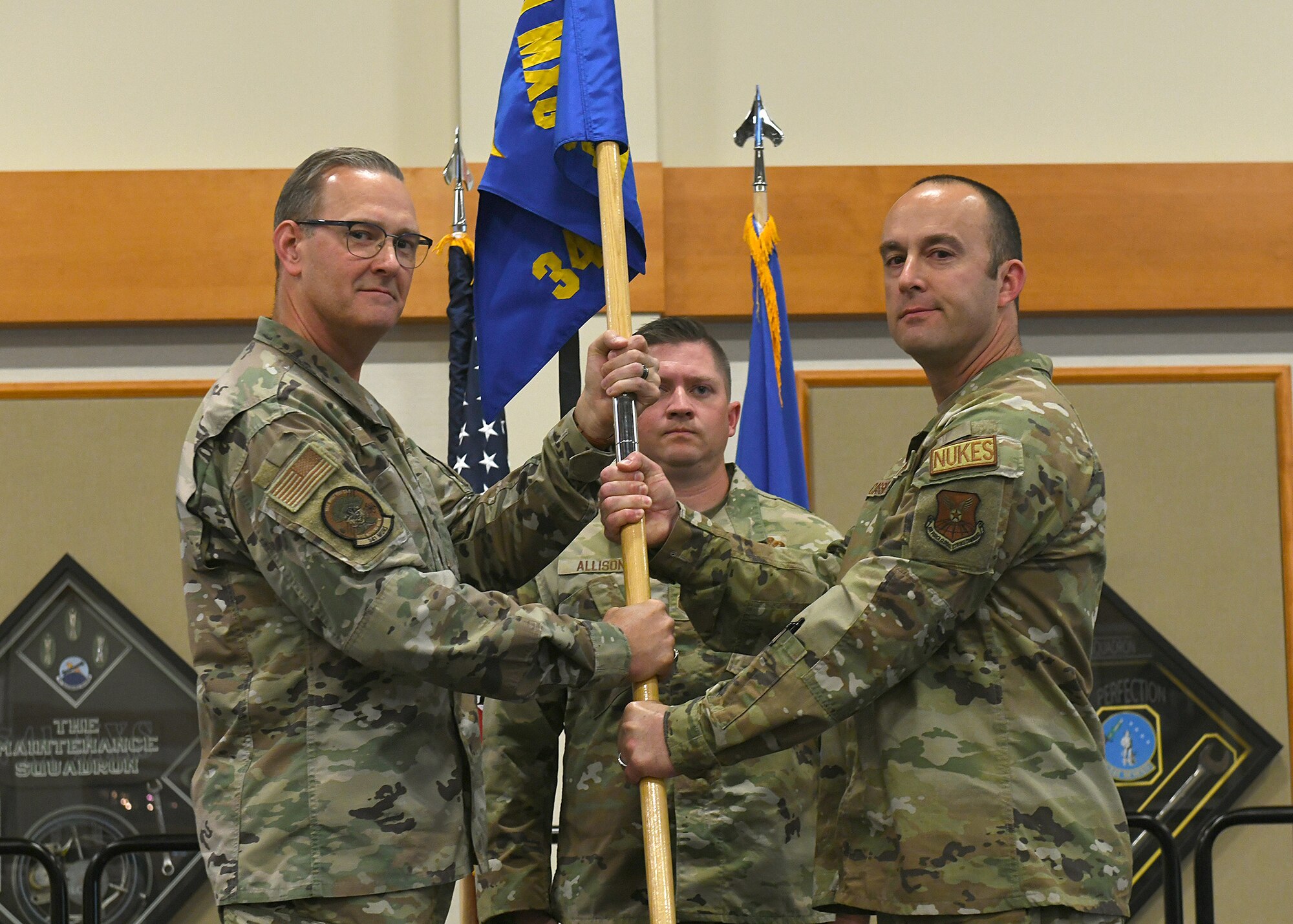Colonel Kenneth Benton and Major Justin Cassidy pose holding a blue flag with gold letters as Major Cassidy takes command of 341st Munitions Squadron.