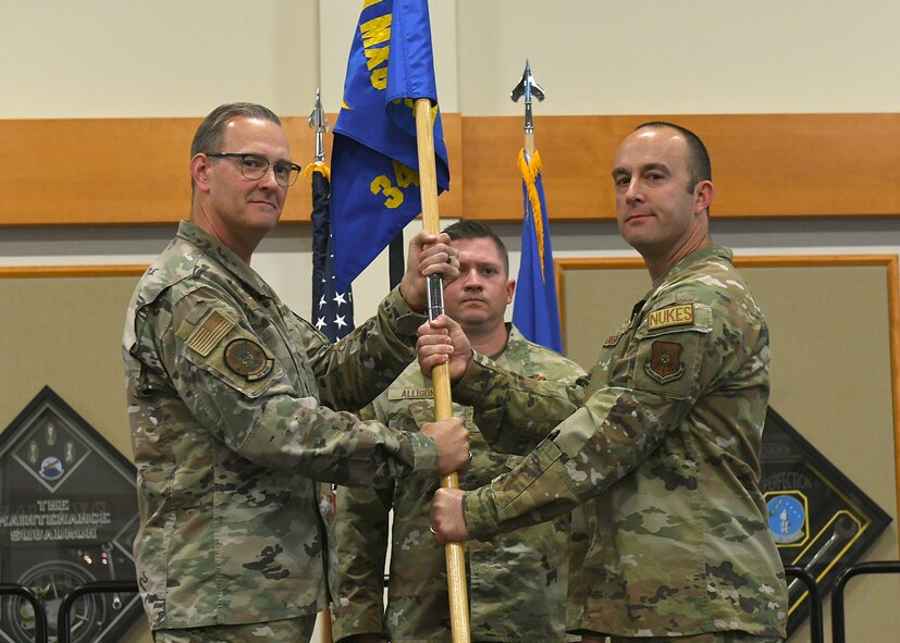 Colonel Kenneth Benton and Major Justin Cassidy pose holding a blue flag with gold letters as Major Cassidy takes command of 341st Munitions Squadron.