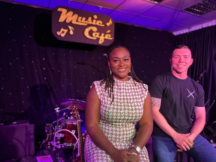 A soldier sits next to a woman on a stage.
