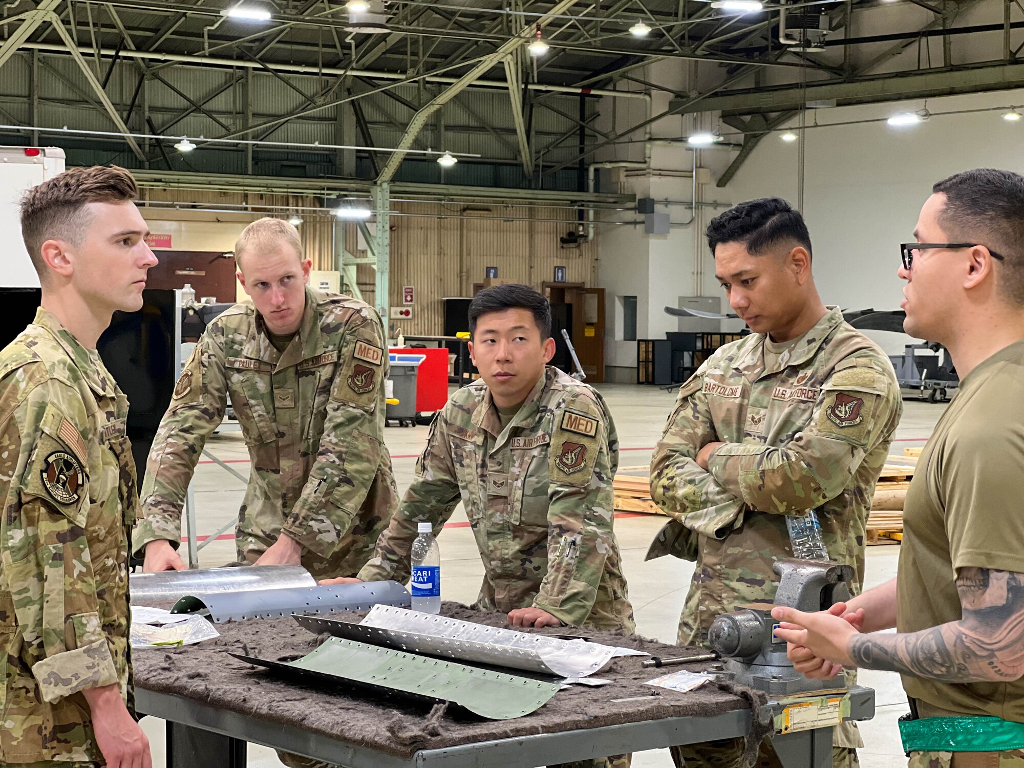 Tech. Sgt. Lawrence Reyes, 374th Maintenance Squadron aircraft structural maintenance shift supervisor, briefs four Airmen about aircraft structural maintenance and sheet metal.