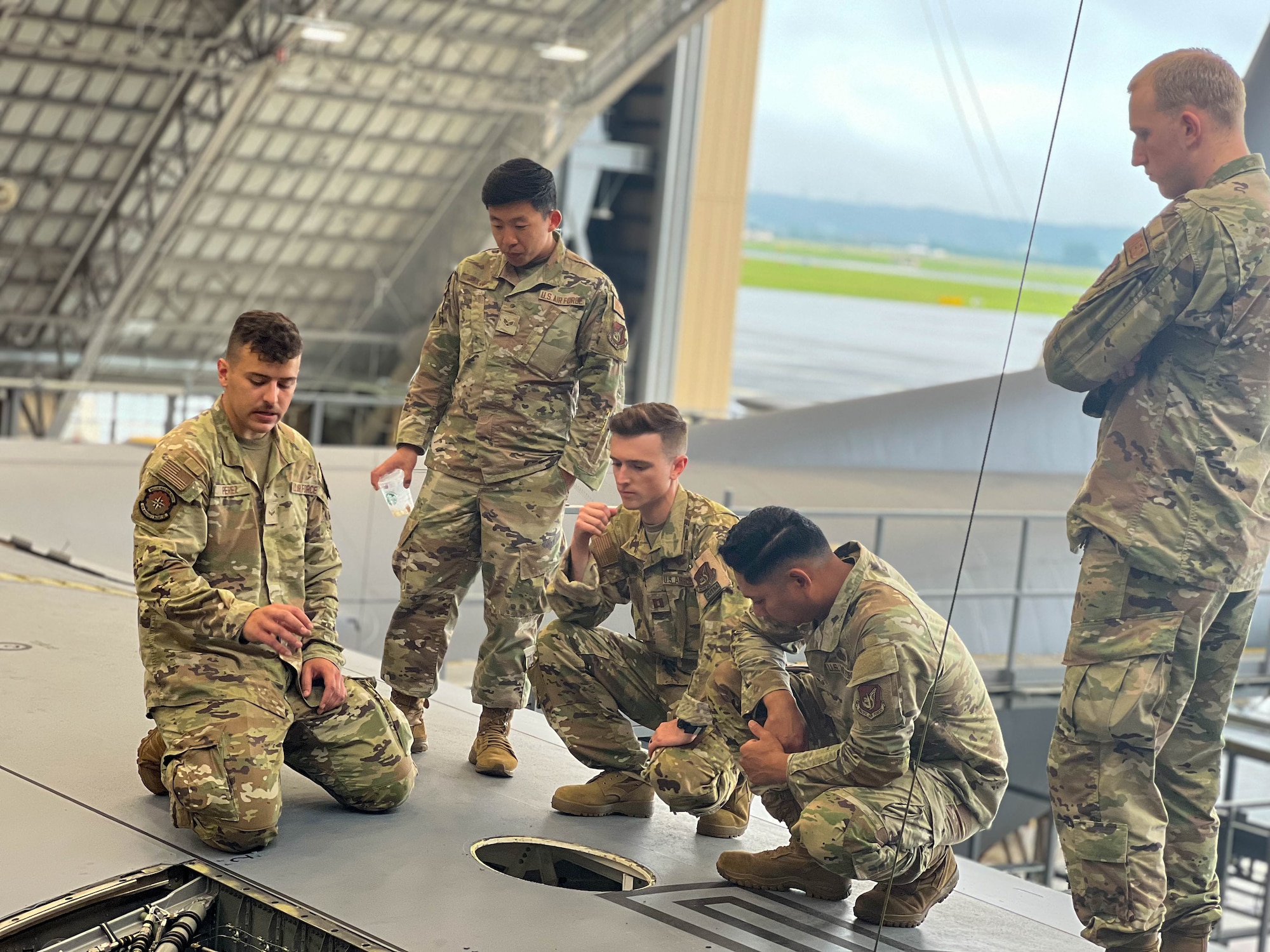 Airman 1st Class Joshua Perez, 374th Aircraft Maintenance Squadron crew chief journeyman, shows four Airmen how to perform a letter check inspection on an MC-130J Commando II.