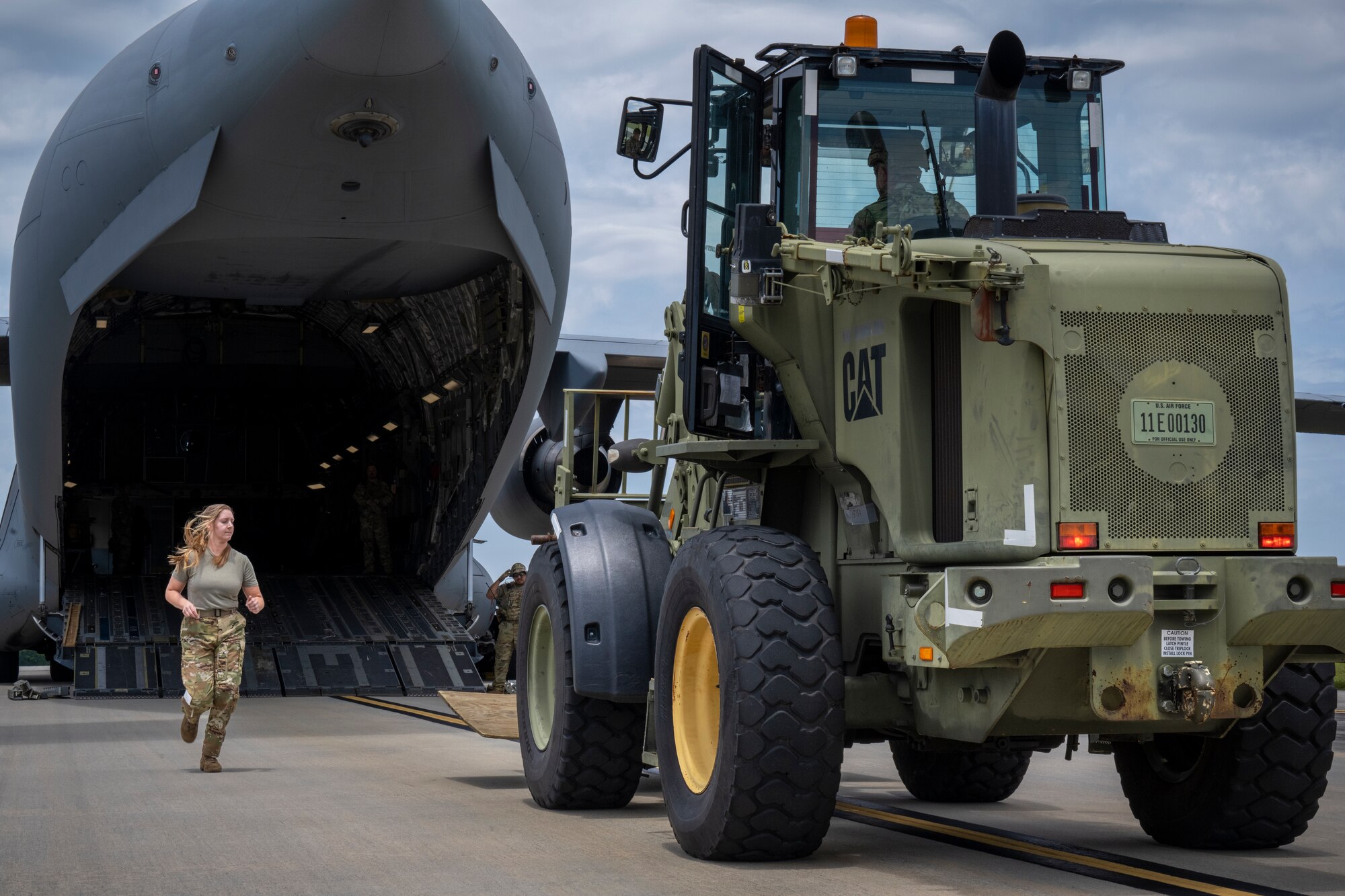 A C-17 Globemaster aircrew loadmaster, left, rushes to speak to U.S. Air Force Staff Sgt. Jose Suarez, right, 621st Mobility Support Operations Squadron enlisted air/ground liason element (EAGLE) team member, before marhsalling the forklift onto the C-17 during Exercise SWAMP AVENGER at North Field, South Carolina, May 25, 2023.
