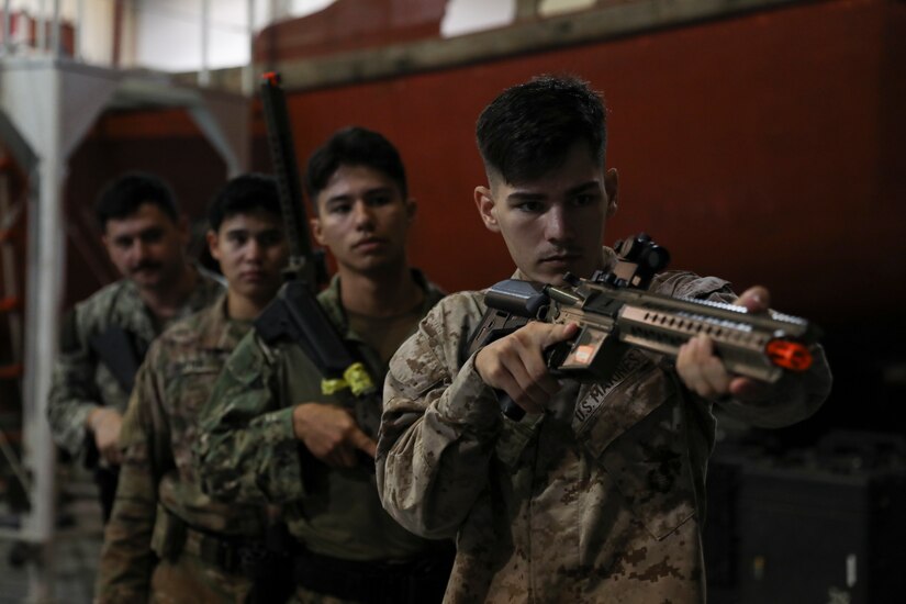 A Marine holding up a weapon leads a team of other Marines.