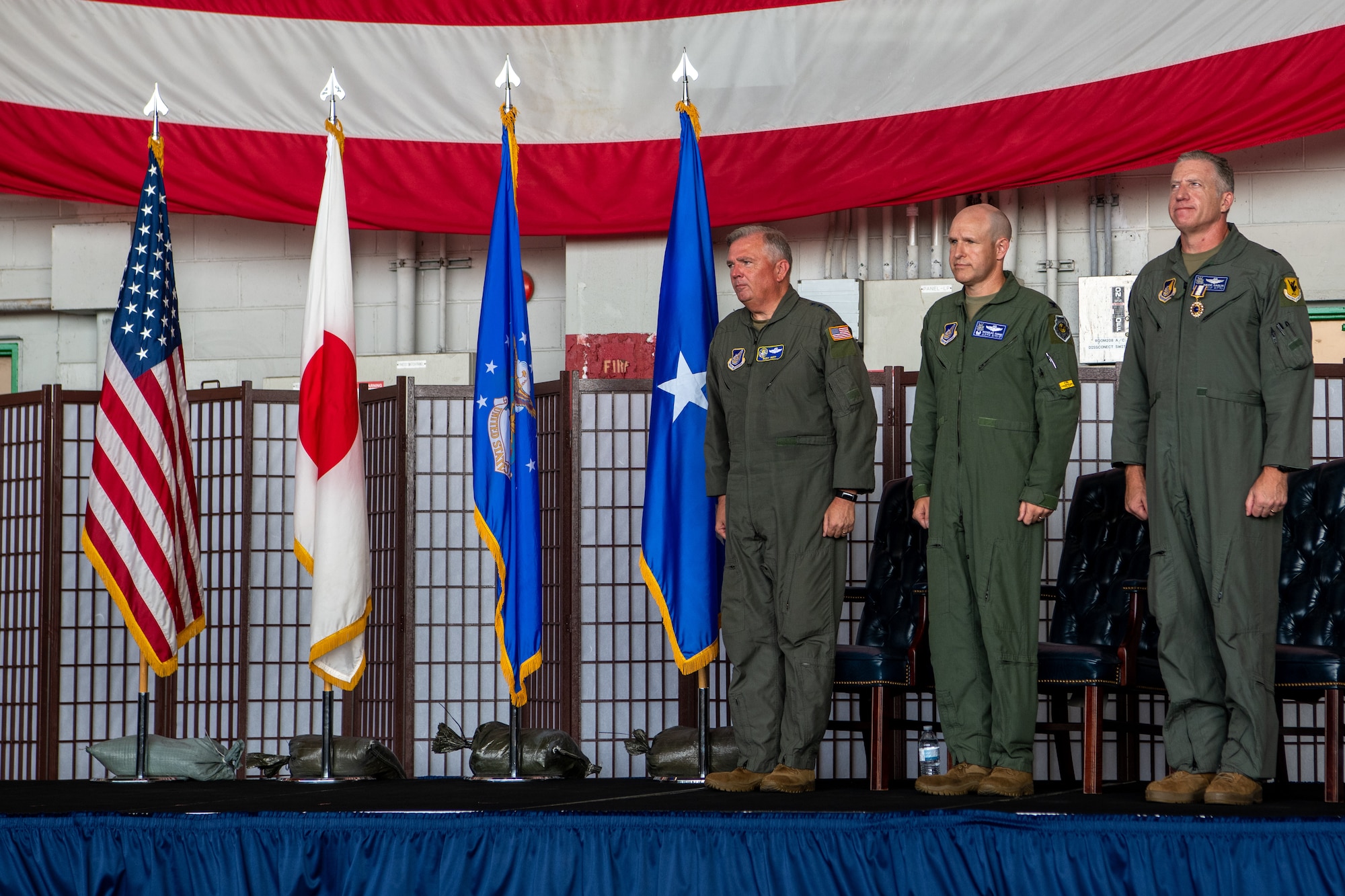 Three men stand on stage.
