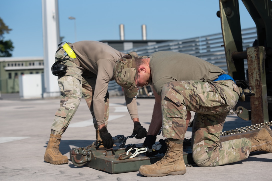 U.S. Airmen with the 123rd Contingency Response Element, 123rd Airlift Wing, Kentucky National Guard, secure chains on a forklift in preparation to unload cargo in support of exercise Air Defender 2023 (AD23) at Wunstorf Air Base, Germany, June 4, 2023. Exercise AD23 integrates both U.S and allied air-power to defend shared values, while leveraging and strengthening vital partnerships to deter aggression around the world. (U.S. Air National Guard photo by Senior Master Sgt. Vicky Spesard)