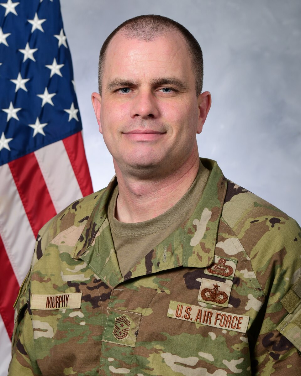 A photo of a man in from of the U.S. Flag.