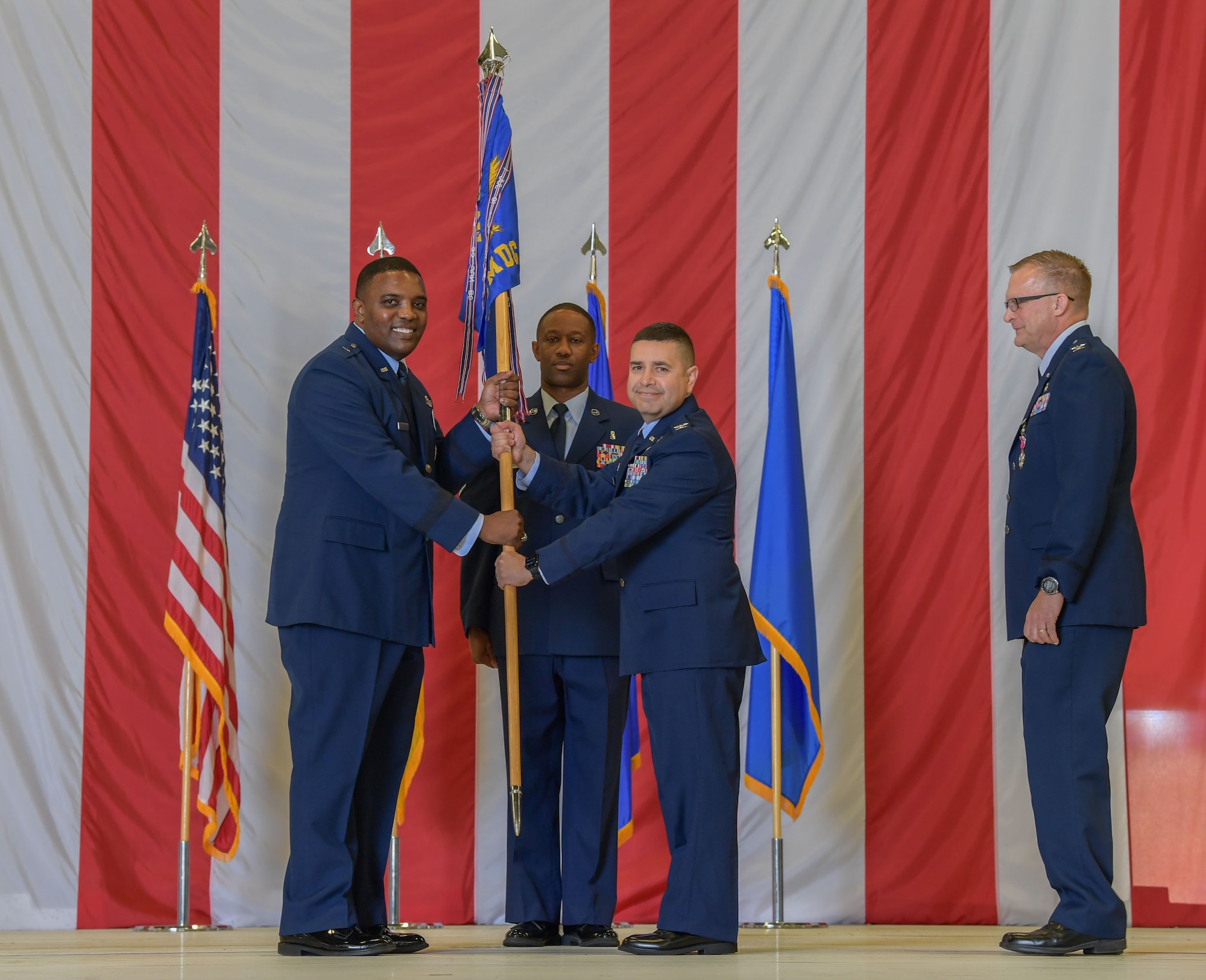 U.S. Air Force Brig. Gen. Otis C. Jones, left, 86th Airlift Wing commander, passes a guidon to Col. Dwayne Baca, right, 86th Medical Group incoming commander, during the 86th MDG change of command ceremony at Ramstein Air Base, Germany, July 6, 2023. The 86th MDG is accountable for community health care services to 56,000 in the Kaiserslautern Military Community. (U.S. Air Force photo by Airman Trevor Calvert)
