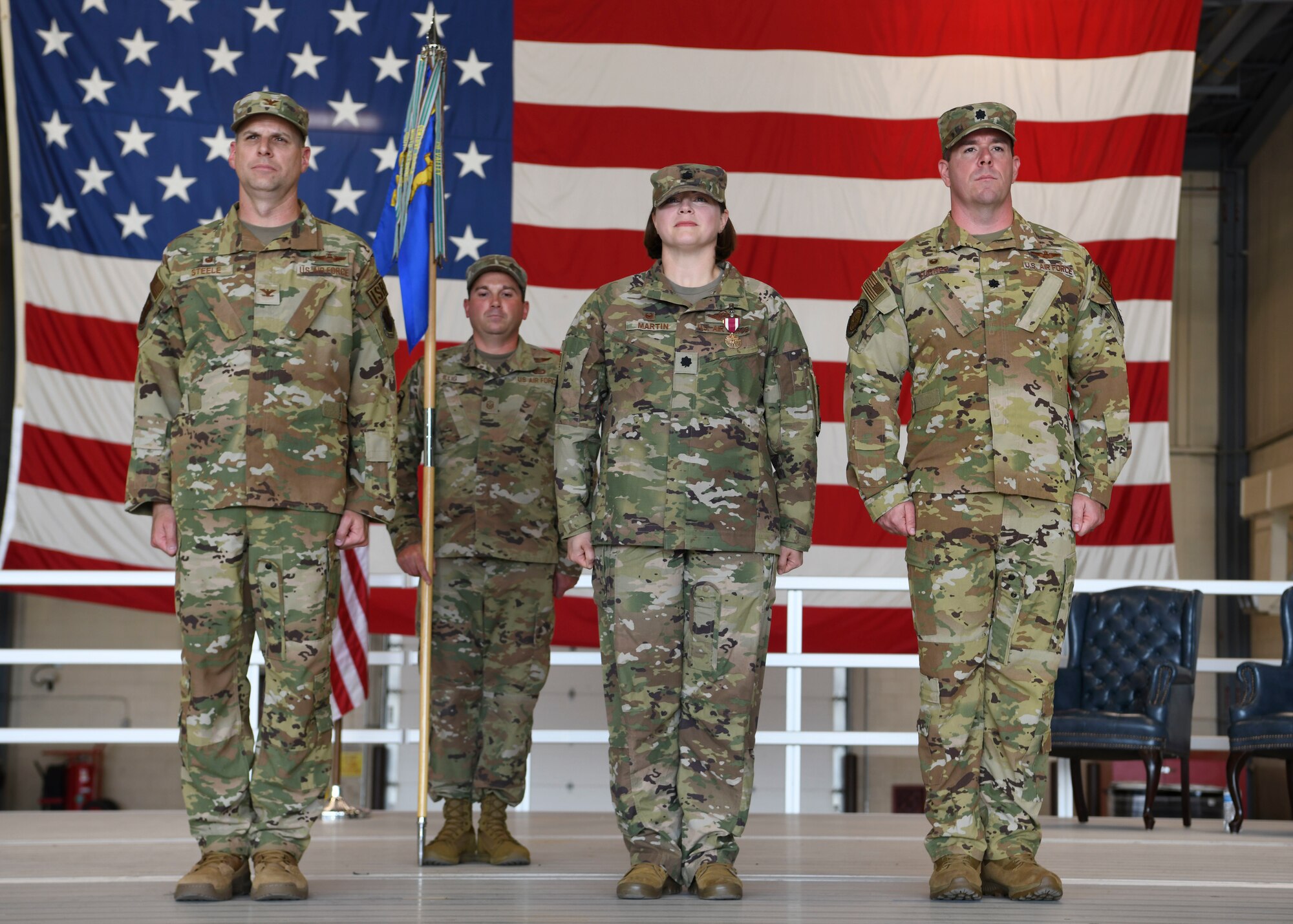 Four people in green uniforms stand together.