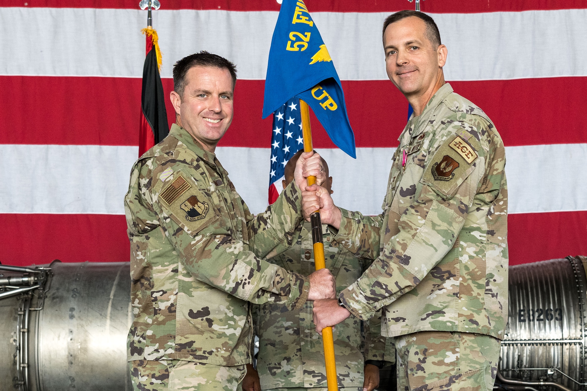 Col. Kevin Crofton, 52nd Fighter Wing commander receives the guidon from Col. James Vinson, 52nd Maintenance Group outgoing commander, as he relinquishes command of the MXG