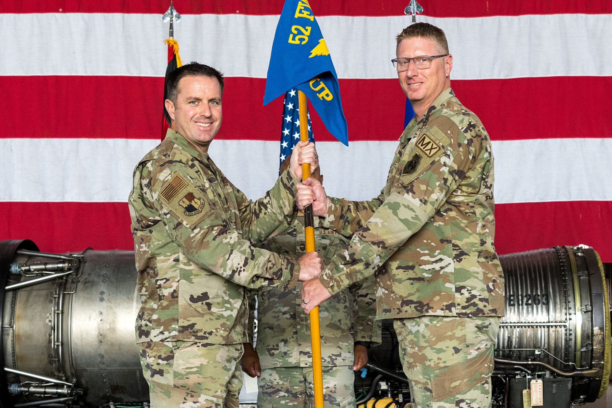 Col. Kevin Crofton, 52nd Fighter Wing commander, passes the guidon to Col. Jason Purdy, 52nd Maintenance Group incoming commander, as he takes command of the MXG