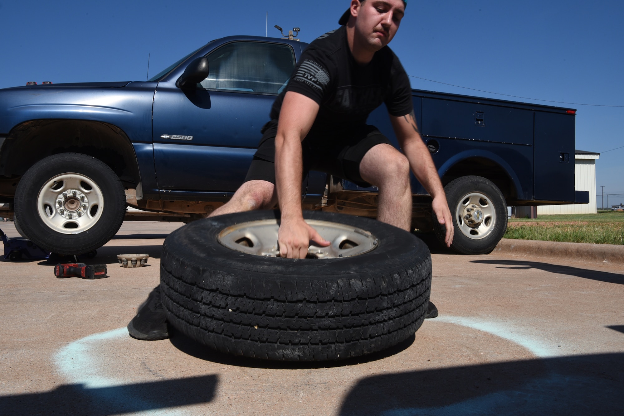 Airman 1st Class Preston Wilkinson, 7th Logistics Readiness Squadron ground transportation support operator, picks up a tire during the LRS Rodeo at Dyess Air Force Base, Texas, June 28, 2023. This is the first rodeo event for the 7th LRS at Dyess, held in celebration of National Logistics Day. (U.S. Air Force photo by Senior Airman Sophia Robello)