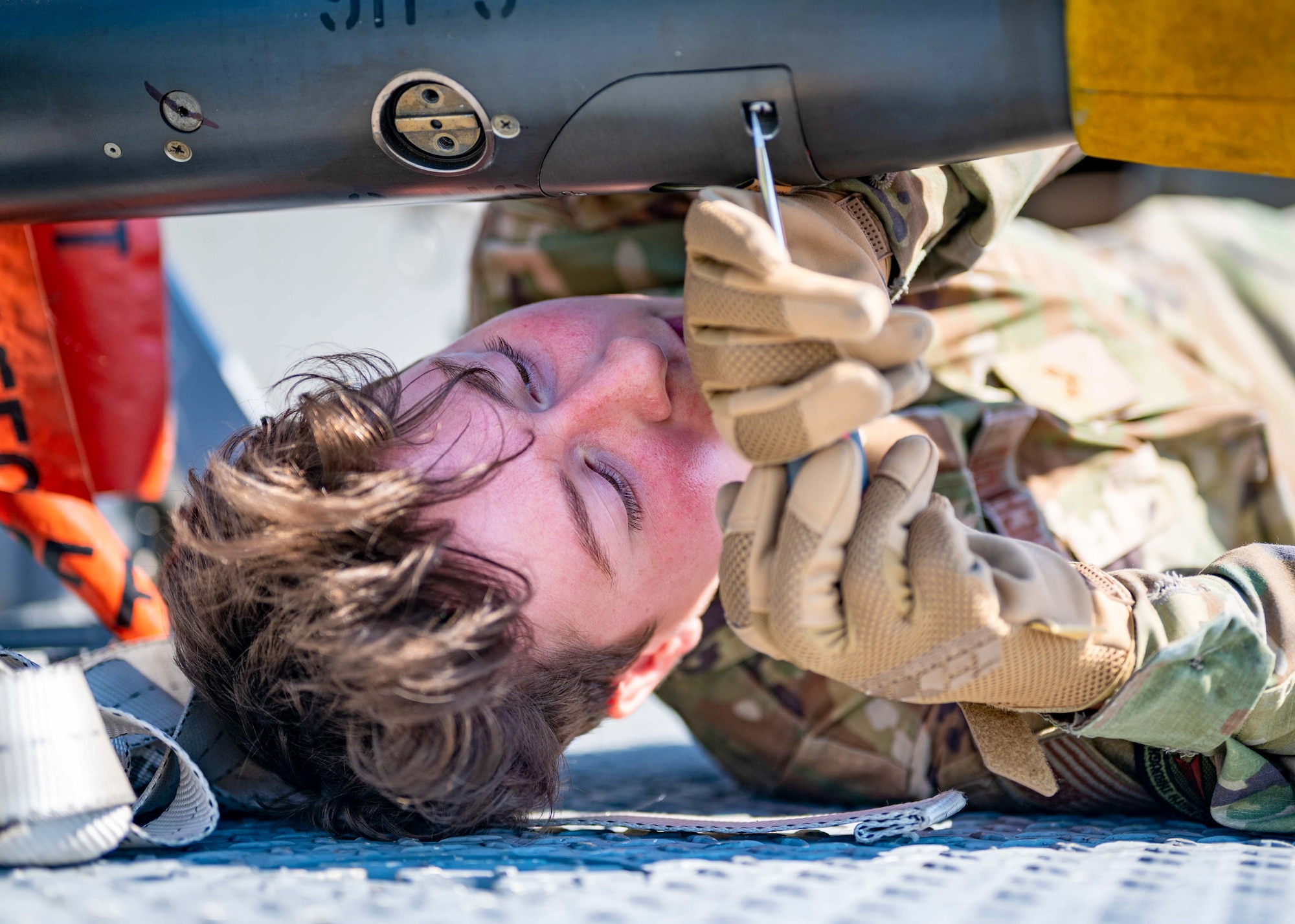 An Airman tightens screws on a missile while loading it onto a transportation unit.