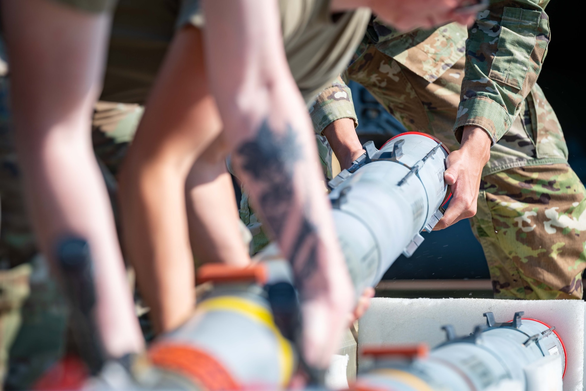 Airmen work together to lift a missile from storage.