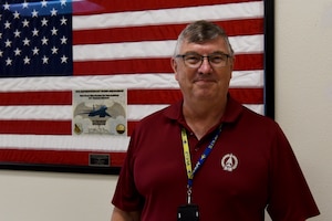 Philip Hermes, 7th Maintenance Group Air Force Engineering Technical Services program weapons system specialist, poses in front of the flag on Dyess Air Force Base, Texas, June 2, 2023. Hermes has served with the B-1B Lancers at Dyess since his arrival here in 1985. (U.S. Air Force photo by Senior Airman Sophia Robello)