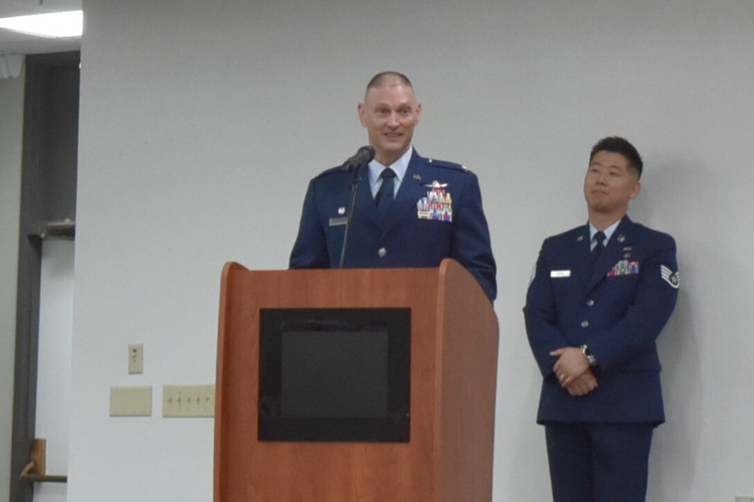Col. John Hollister stands behind a podium.