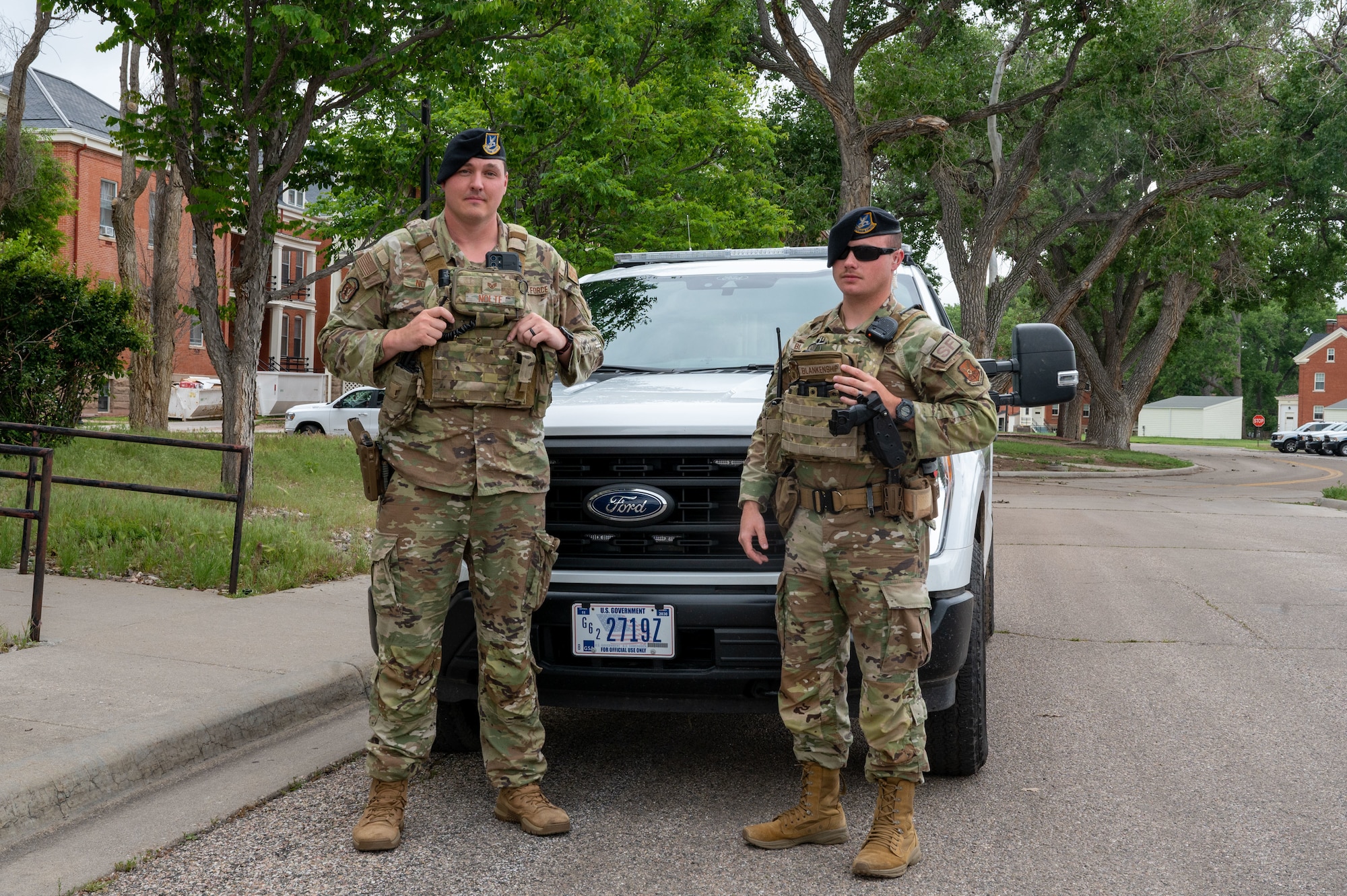 Airmen pose in front of squad car