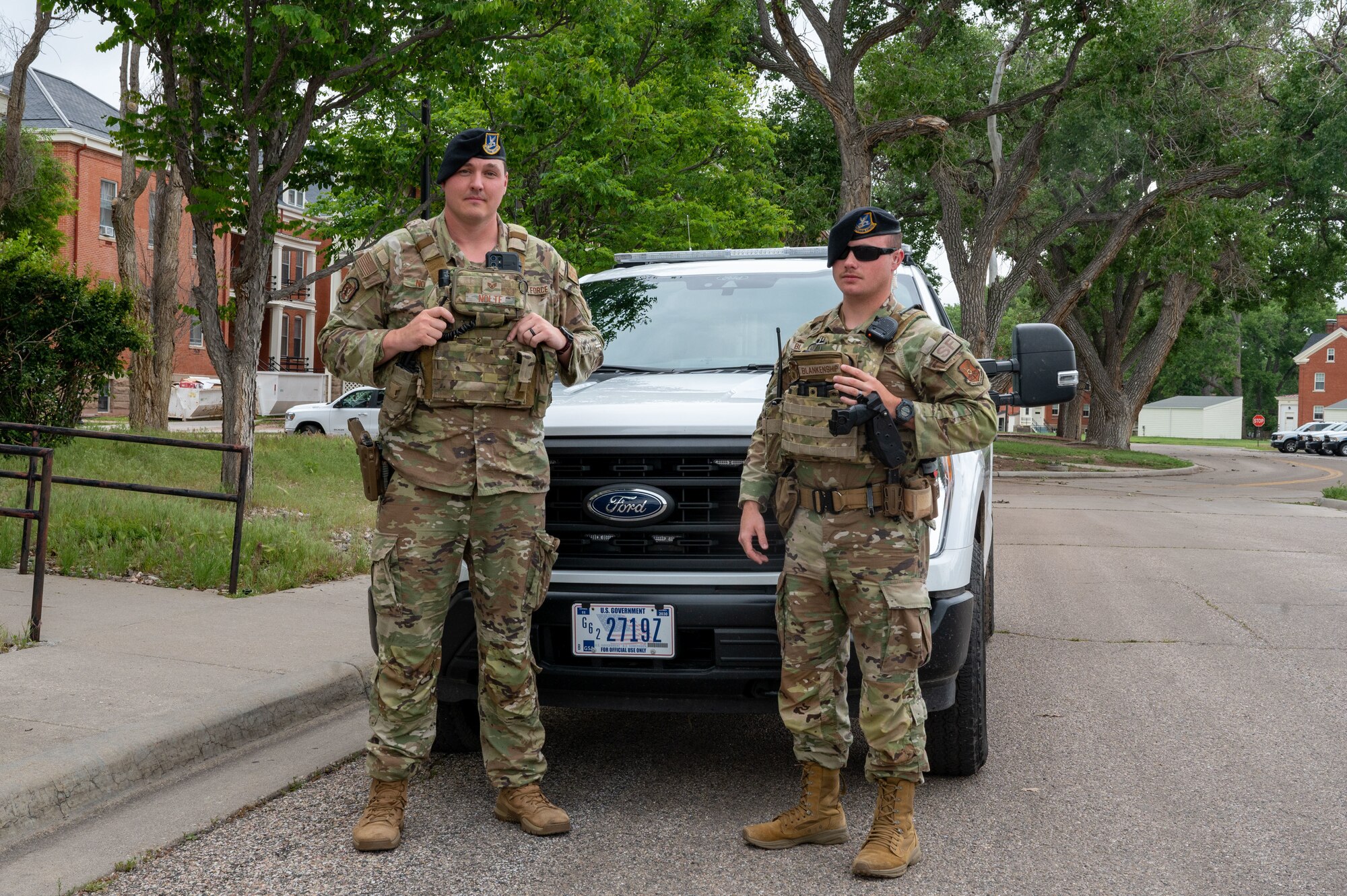Airmen pose in front of squad car