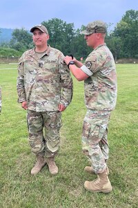 Overall first-place finisher 1st Sgt. Scott Sheroky, left, of the Eastern Army National Guard Aviation Training Site, receives his Governor's Twenty uniform tab from Capt. Shawn Garghill, chief of the Pennsylvania Army National Guard Individual Training Branch, at the conclusion of the annual Governor’s Twenty marksmanship competition July 1, 2023, at Fort Indiantown Gap, Pa. (Courtesy photo)