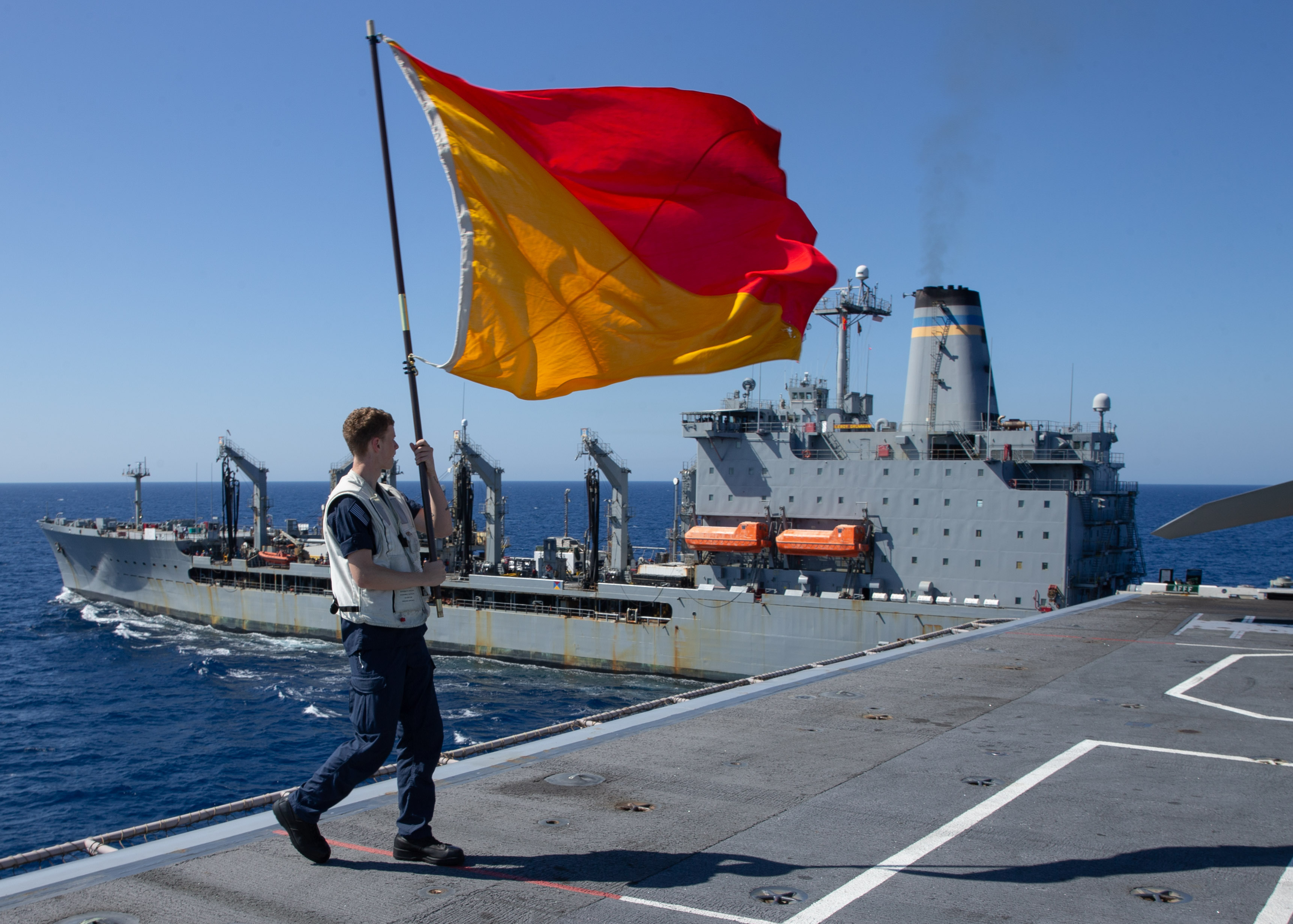 Quartermaster Seaman Apprentice Zachery Teetz signals USNS Leroy Grumman (T-AO 195) from aboard USS Gerald R. Ford, (CVN 78).
