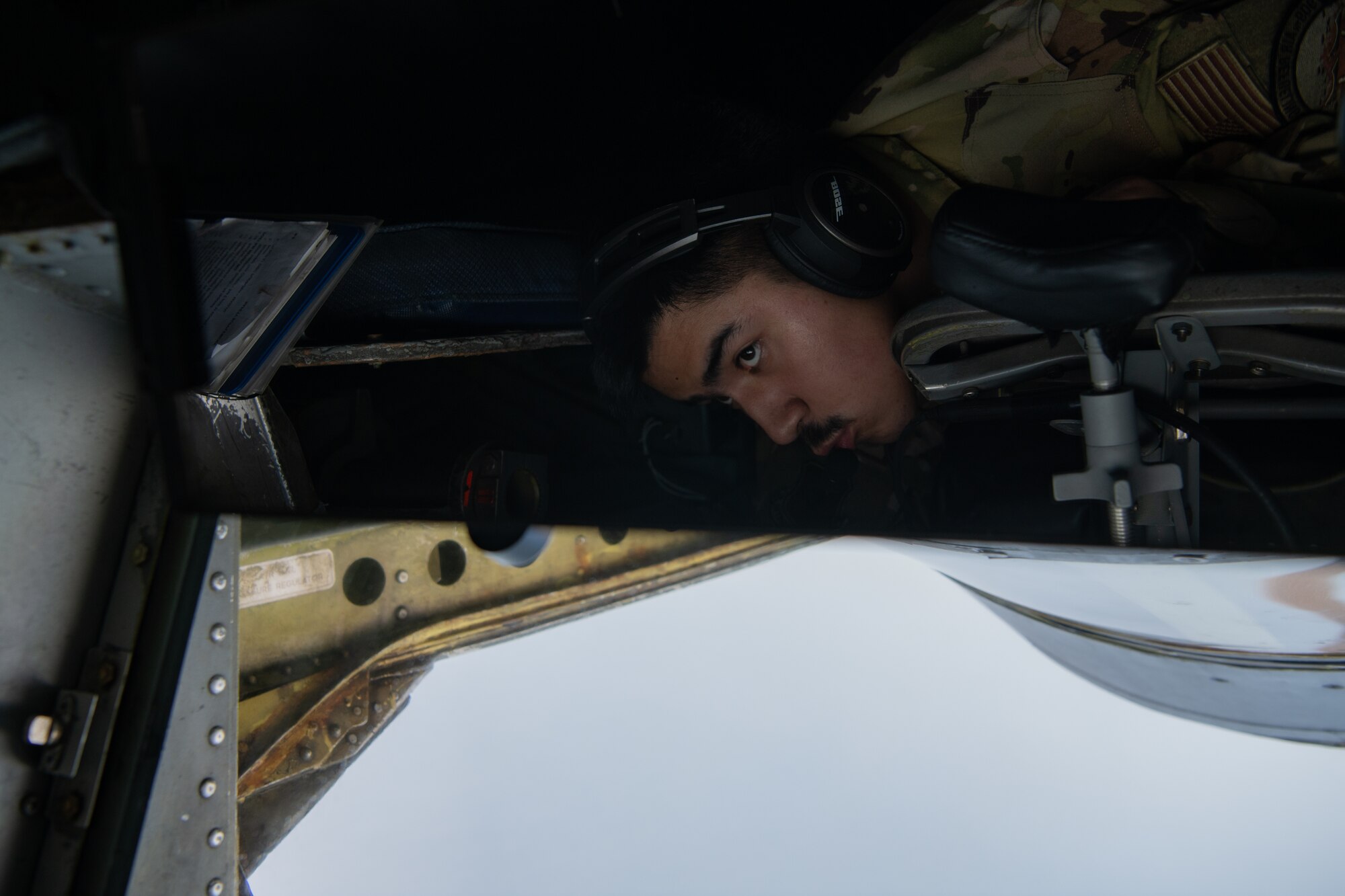 An Airman looks out a window for an aircraft.