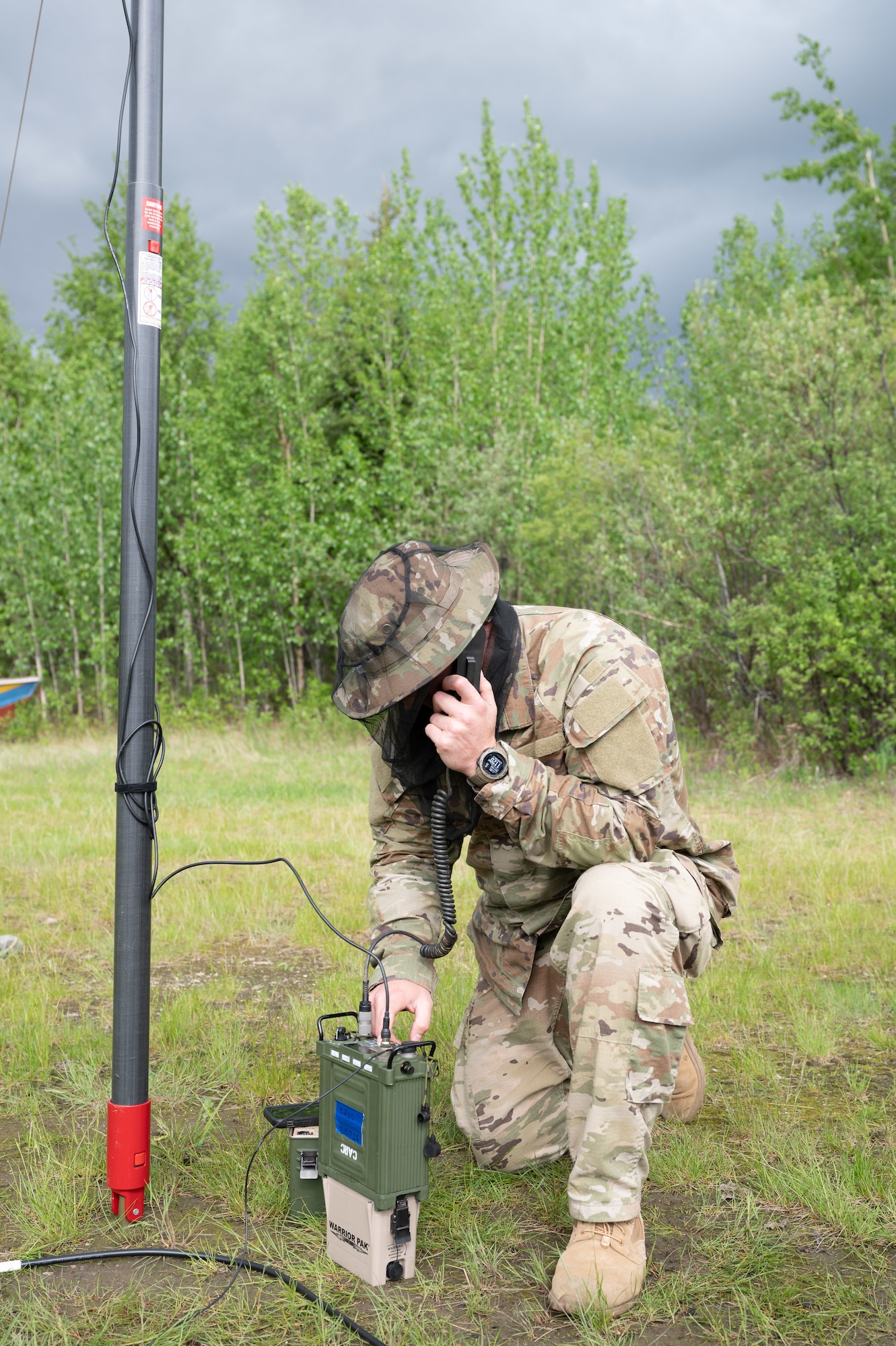 U.S. Air Force Tech Sgt. Collin Lopes, a radio frequency transmission systems specialist, 35th Combat Communications Squadron, Tinker Air Force Base, Oklahoma remotely establishes communication from Coldfoot, Alaska with counterparts at Tinker AFB and in British Columbia as part of Exercise AGILE BLIZZARD-UNIFIED VISION Phase II on June 11, 2023. Lopes wore a net to protect his face from mosquitos which were just one of the environmental factors that made working above the arctic circle challenging. (U.S. Air Force photo by Staff Sgt. Dana Tourtellotte)