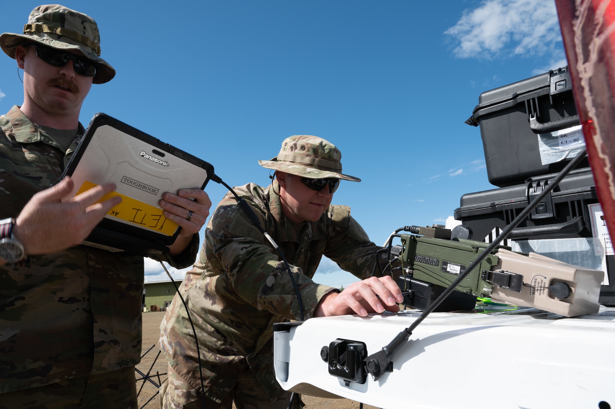 U.S. Air Force Tech Sgt. Laramie Grisba (left) and Tech Sgt. Collin Lopes (right) radio frequency transmission systems specialists from the 55th and 35th Combat Communications Squadrons, Tinker Air Force Base, Oklahoma set up a high frequency radio communication device in Coldfoot, Alaska as part of Phase 2 of AGILE BLIZZARD-UNIFIED VISION June 11, 2023. This radio device provided both visual and auditory communication capabilities. (U.S. Air Force photo by Staff Sgt. Dana Tourtellotte)