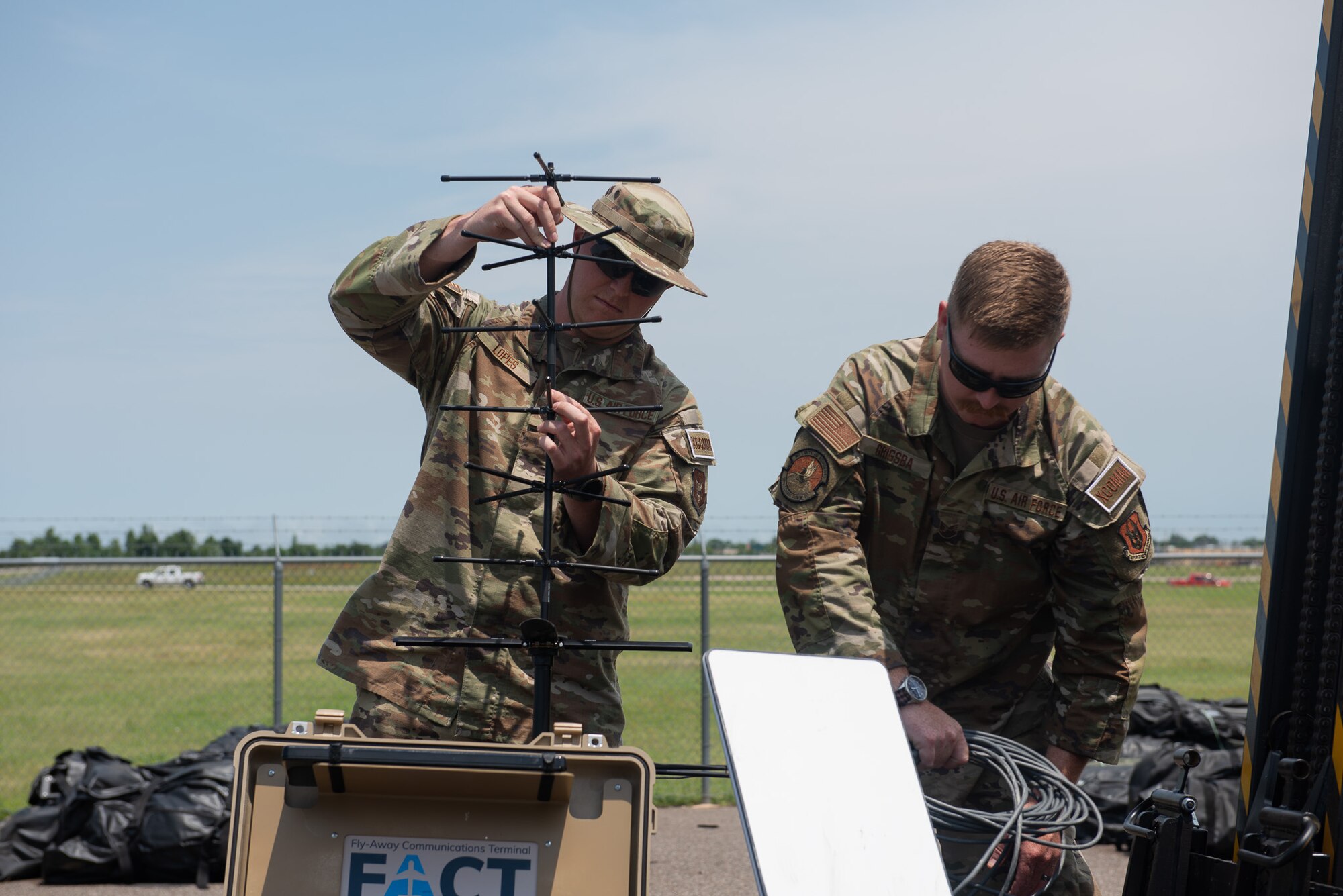 U.S. Air Force Tech. Sgt. Collin Lopes (left), 35th Combat Communications Squadron radio frequency transmission systems specialist, and Tech. Sgt. Laramie Grigsba, 55th CBCS radio frequency transmission systems specialist, establish communications with mobile internet kit while testing equipment, June 21, 2023, at Tinker Air Force Base, Oklahoma. Exercise AGILE BLIZZARD UNIFIED VISION had a conglomerate of expeditionary and combat communicators establishing a communications infrastructure at Tinker AFB, Comox, Canada, and Coldfoot, Alaska. (U.S. Air Force photo by 1st Lt. Hailey Malay)