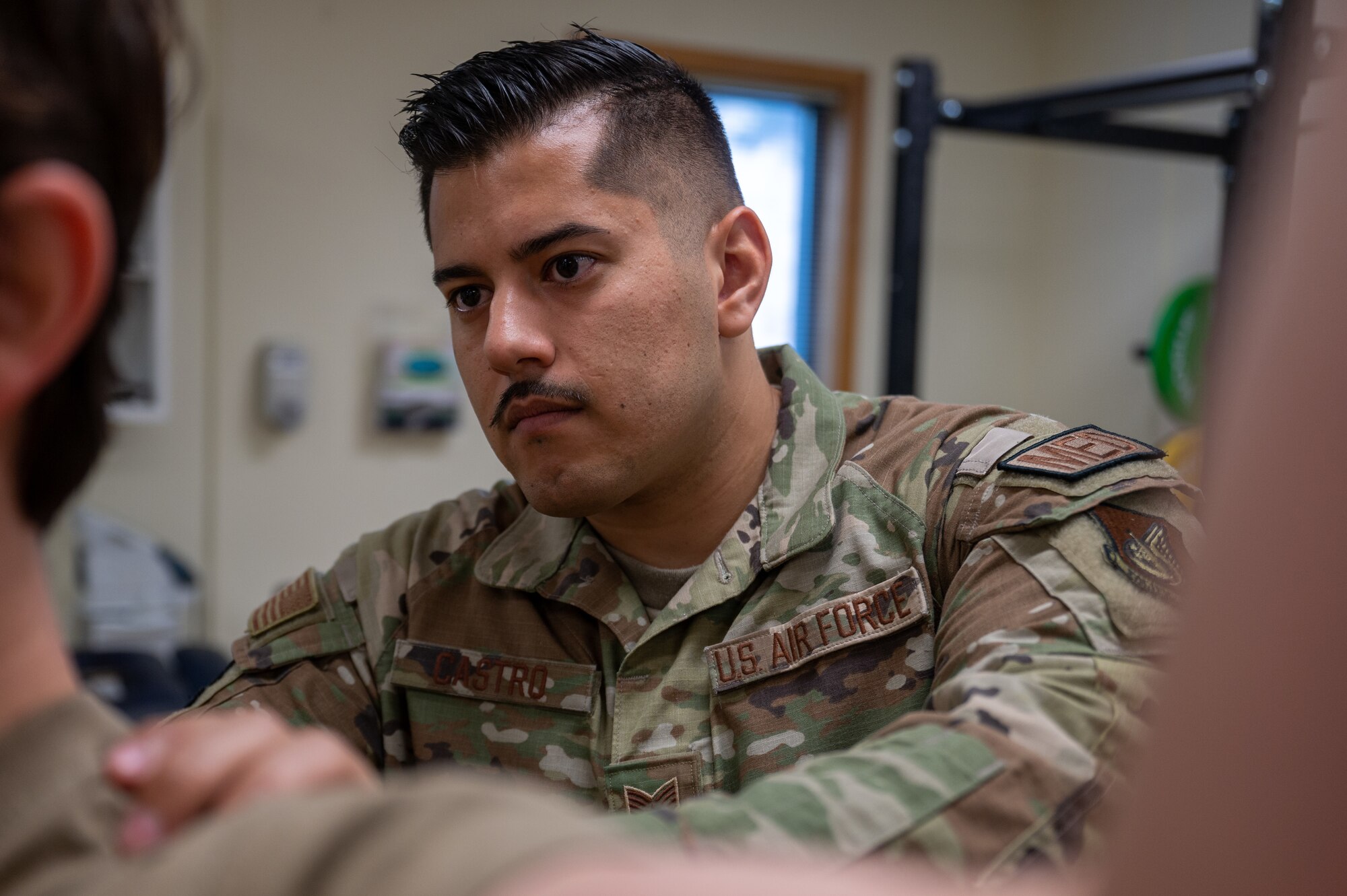 SSgt Alejandro Castro shows the location his patient should focus when performing an exercise during a therapy session at Kunsan Air Base, Republic of Korea, July 7, 2023.