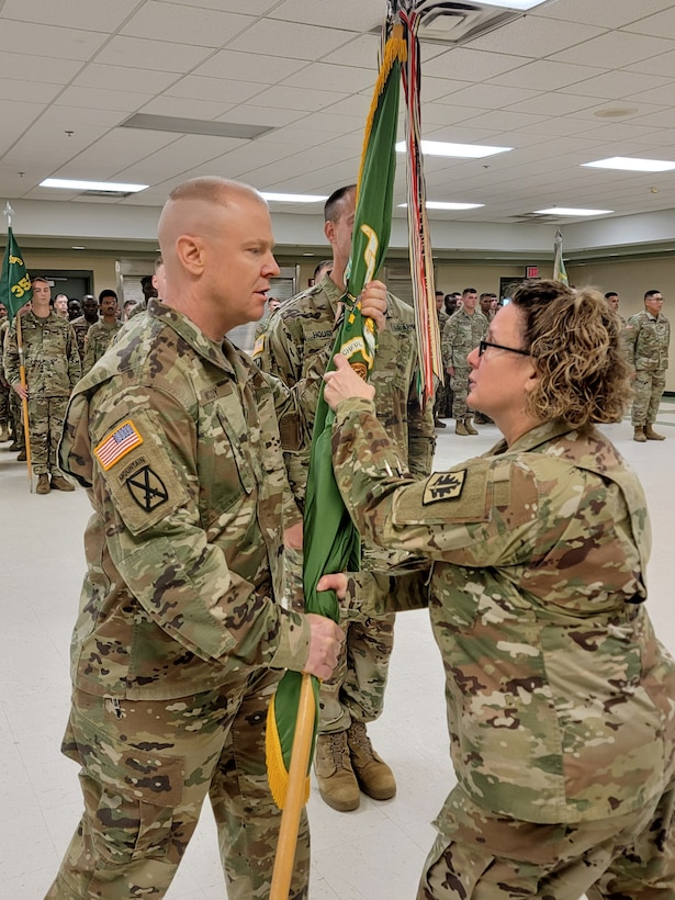 A Soldier passes the military unit colors to another Soldier in a formation.