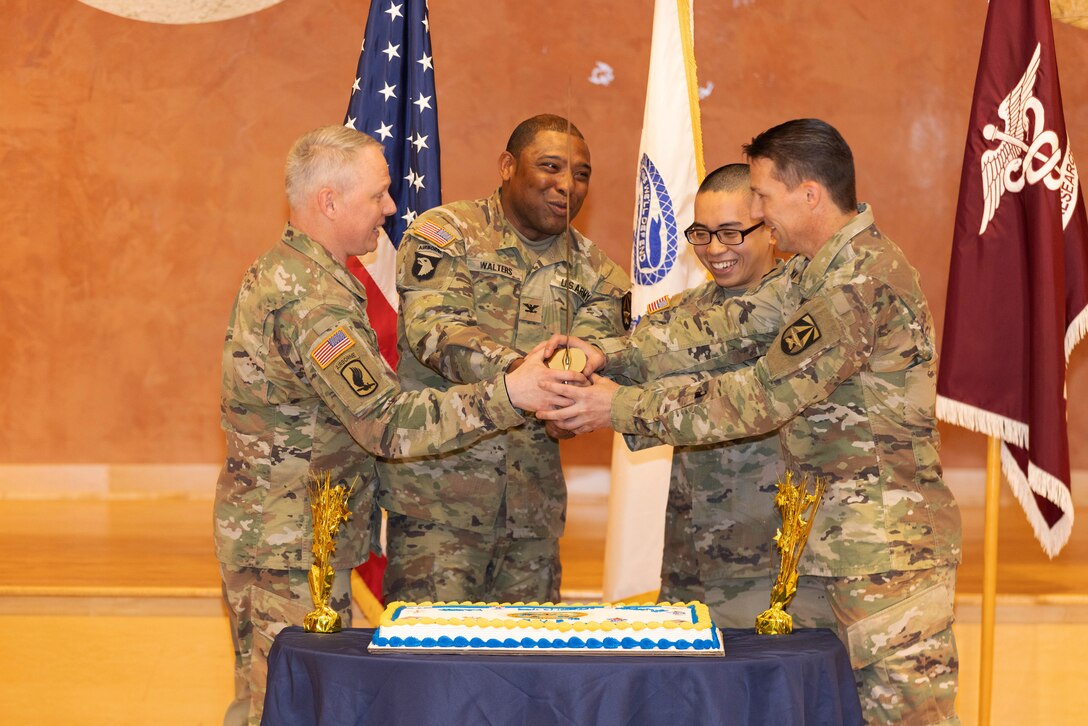 From left to right, Command Sgt. Maj. Donald G. Gross, Col. Kenneth Walters, chief of staff, Spc. Jacob Masecampo, medical logistics, Col. Chad Koenig, commander perform a cake cutting ceremony to celebrate the Army 248th birthday. (U.S. Army photo by Tyra Breaux/RELEASED).